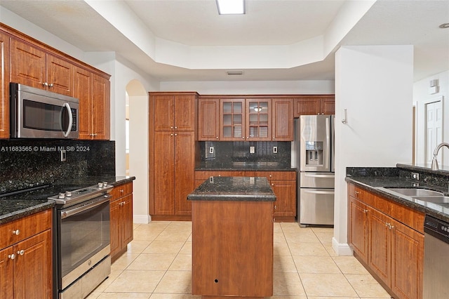 kitchen featuring dark stone countertops, stainless steel appliances, backsplash, and a kitchen island