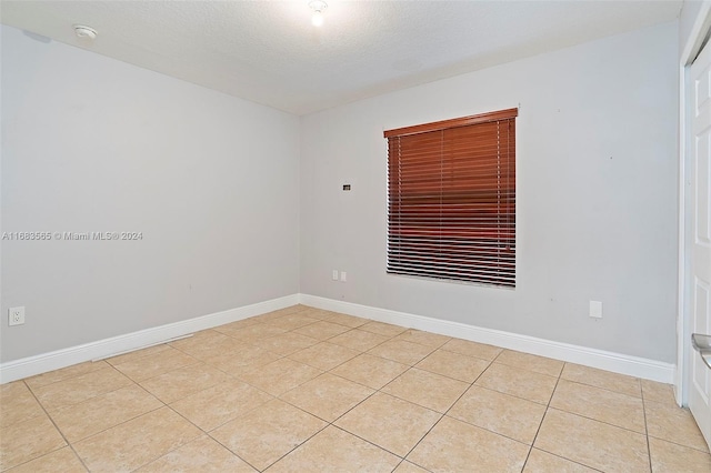 tiled spare room featuring a textured ceiling