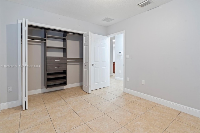 unfurnished bedroom with a closet, a textured ceiling, and light tile patterned floors