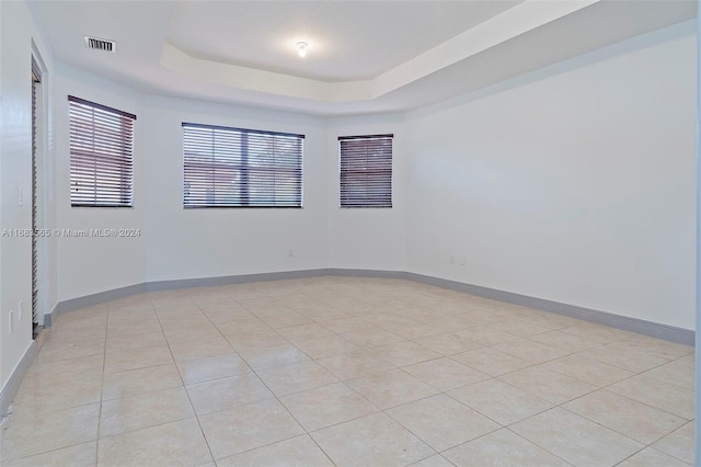 empty room featuring light tile patterned floors and a raised ceiling