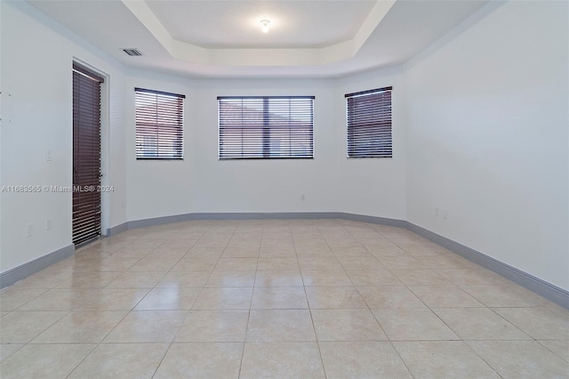 tiled spare room featuring a raised ceiling