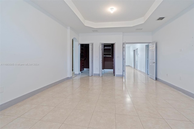 empty room featuring light tile patterned floors and a raised ceiling