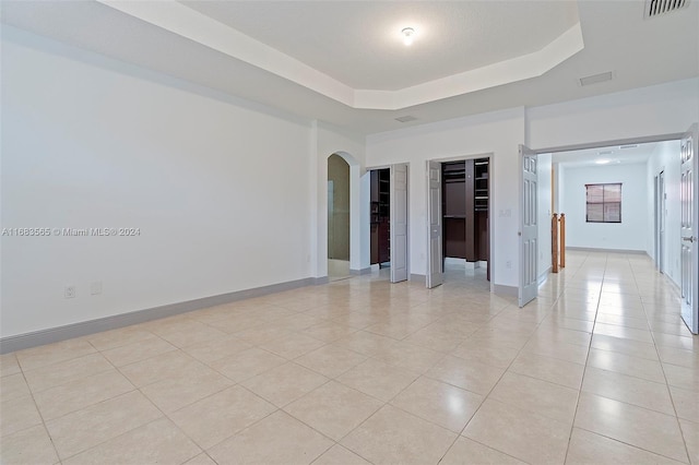 spare room with light tile patterned floors and a tray ceiling