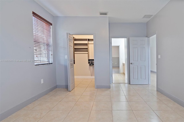 unfurnished bedroom featuring a closet, a spacious closet, and light tile patterned floors