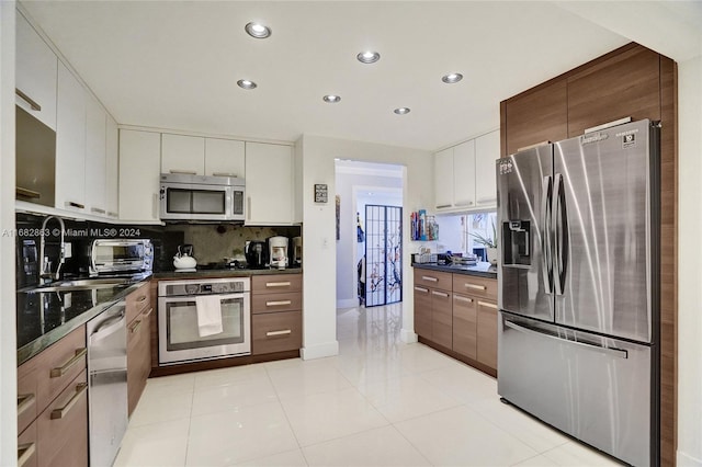 kitchen with white cabinets, light tile patterned floors, backsplash, sink, and stainless steel appliances