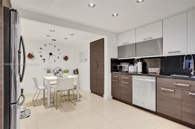 kitchen with sink, white cabinetry, stainless steel appliances, decorative backsplash, and light tile patterned floors