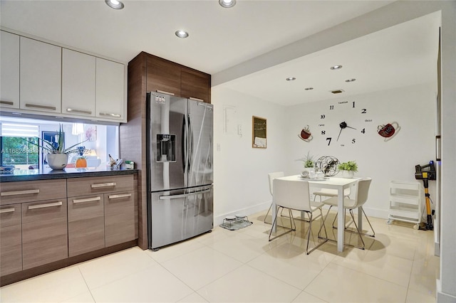 kitchen featuring stainless steel fridge, white cabinets, and light tile patterned flooring