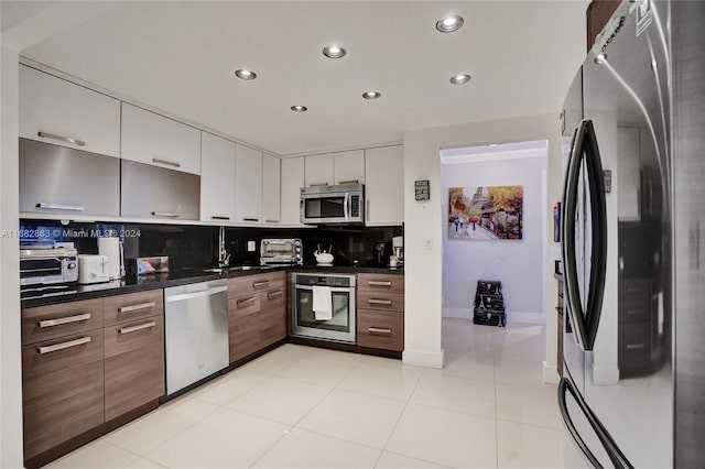 kitchen with white cabinets, tasteful backsplash, light tile patterned floors, sink, and stainless steel appliances