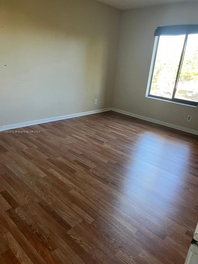 unfurnished room with dark wood-type flooring