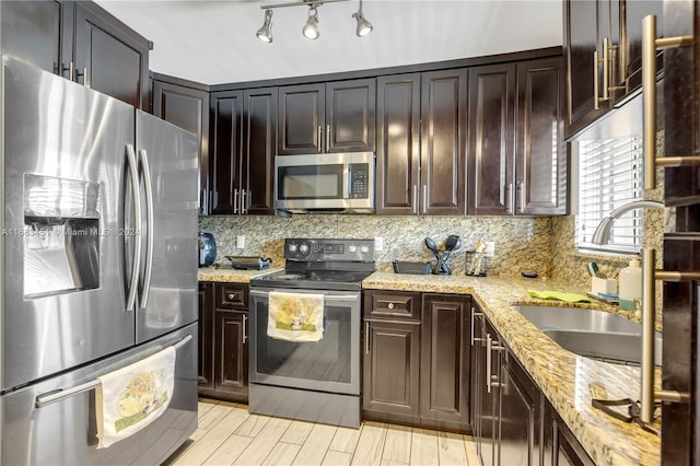 kitchen featuring dark brown cabinets, backsplash, light stone countertops, sink, and stainless steel appliances