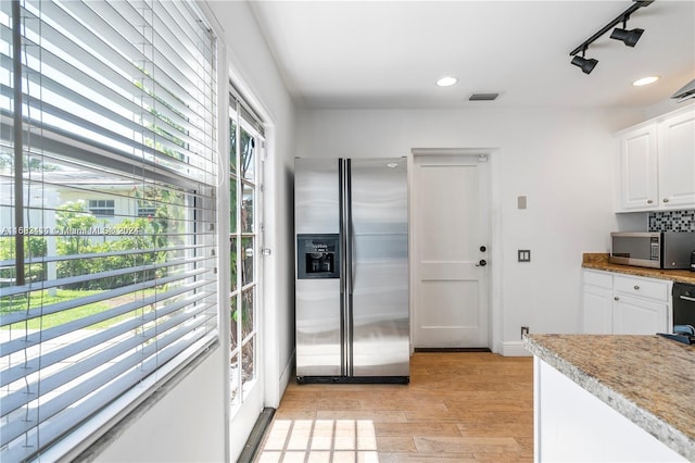 kitchen featuring appliances with stainless steel finishes, light hardwood / wood-style flooring, white cabinetry, and a wealth of natural light