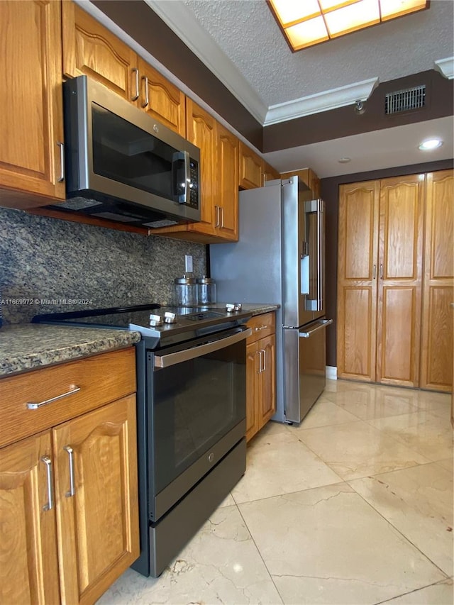 kitchen with decorative backsplash, dark stone countertops, ornamental molding, appliances with stainless steel finishes, and a textured ceiling