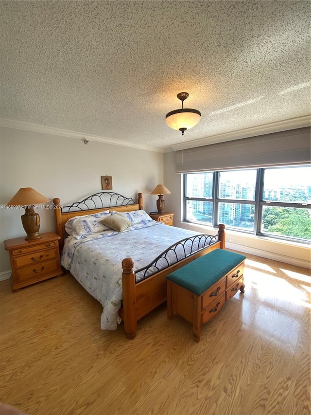 bedroom with crown molding, a textured ceiling, and light hardwood / wood-style floors