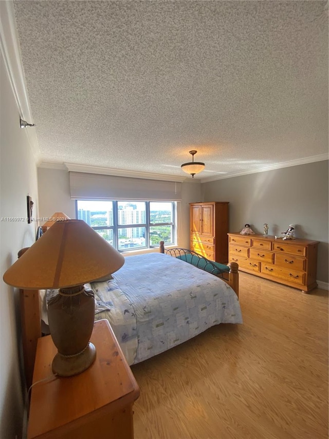 bedroom with light hardwood / wood-style floors, crown molding, and a textured ceiling