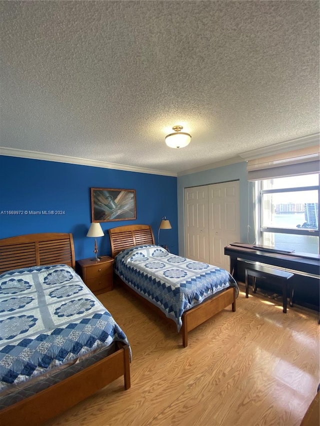 bedroom featuring a closet, crown molding, hardwood / wood-style flooring, and a textured ceiling