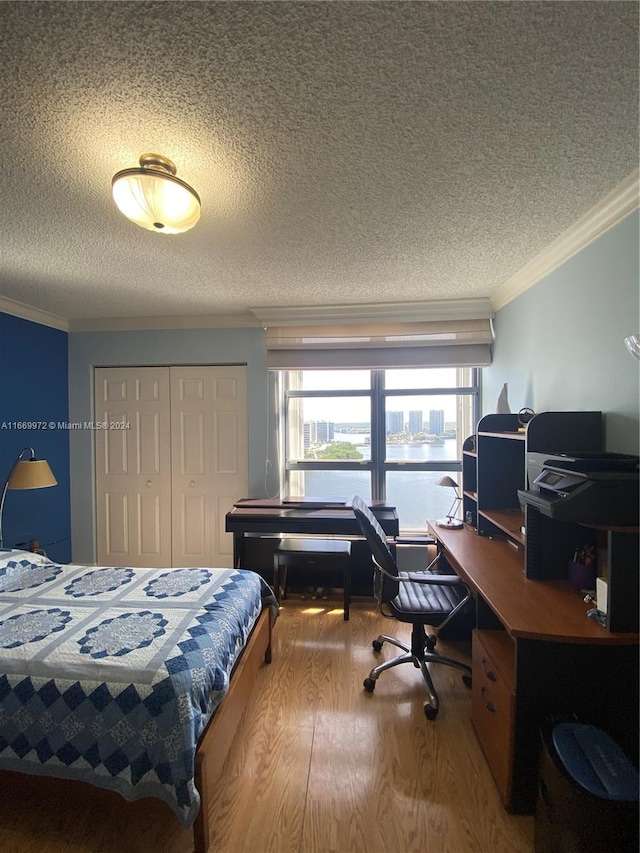 bedroom featuring ornamental molding, a textured ceiling, wood-type flooring, and a closet