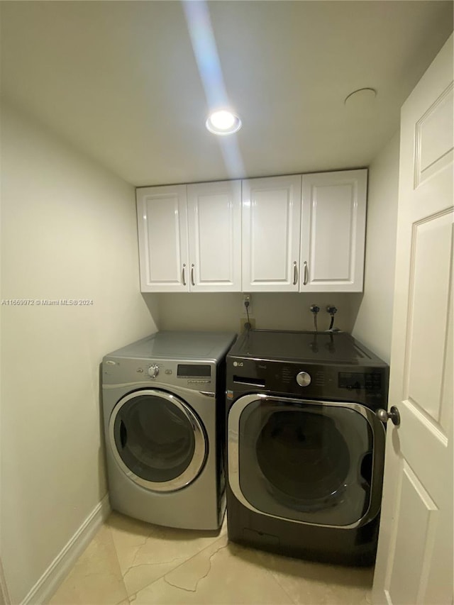 clothes washing area with cabinets and separate washer and dryer