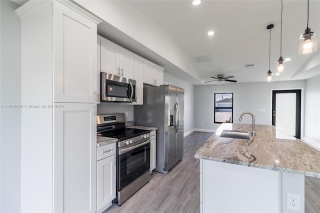 kitchen with lofted ceiling, sink, decorative light fixtures, white cabinetry, and appliances with stainless steel finishes