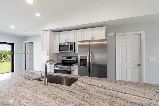 kitchen with light stone countertops, sink, white cabinetry, stainless steel appliances, and lofted ceiling