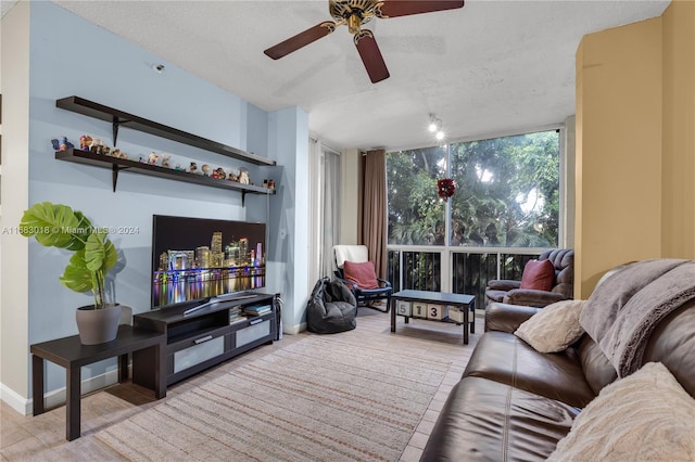 living room featuring ceiling fan, a textured ceiling, and a wall of windows