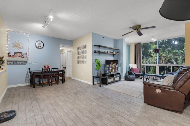 living room with a textured ceiling, light wood-type flooring, and ceiling fan