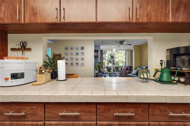 interior space with tile countertops and ceiling fan