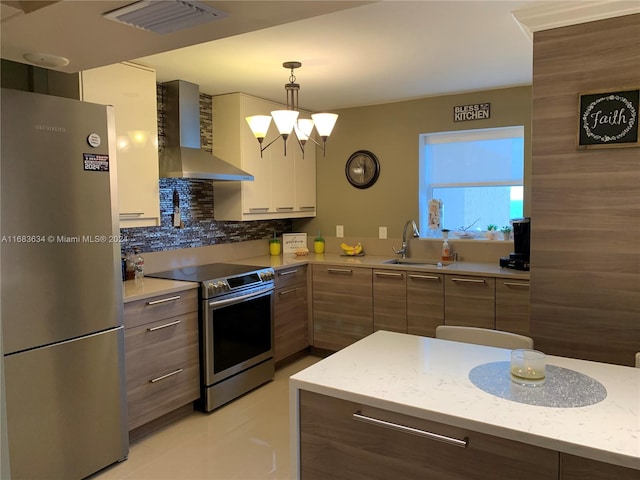 kitchen featuring wall chimney exhaust hood, stainless steel appliances, sink, pendant lighting, and tasteful backsplash