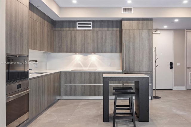 kitchen featuring light tile patterned flooring, stainless steel oven, and sink