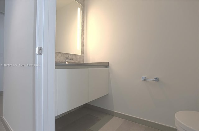 half bath featuring decorative backsplash, toilet, vanity, and baseboards