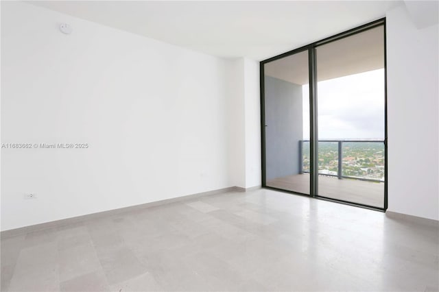 spare room featuring floor to ceiling windows and baseboards