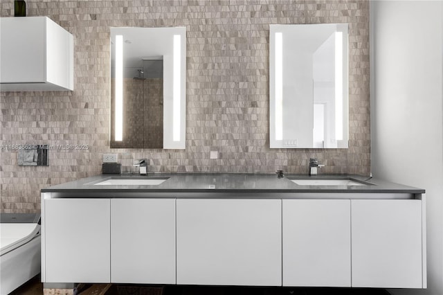 bathroom with double vanity, toilet, tasteful backsplash, and a sink