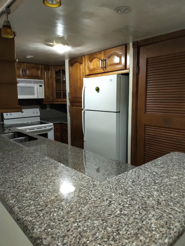 kitchen with white appliances and dark stone counters