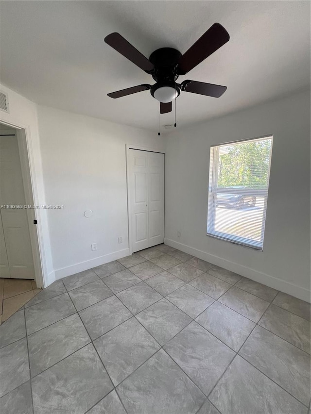 unfurnished bedroom featuring a closet, light tile patterned flooring, and ceiling fan