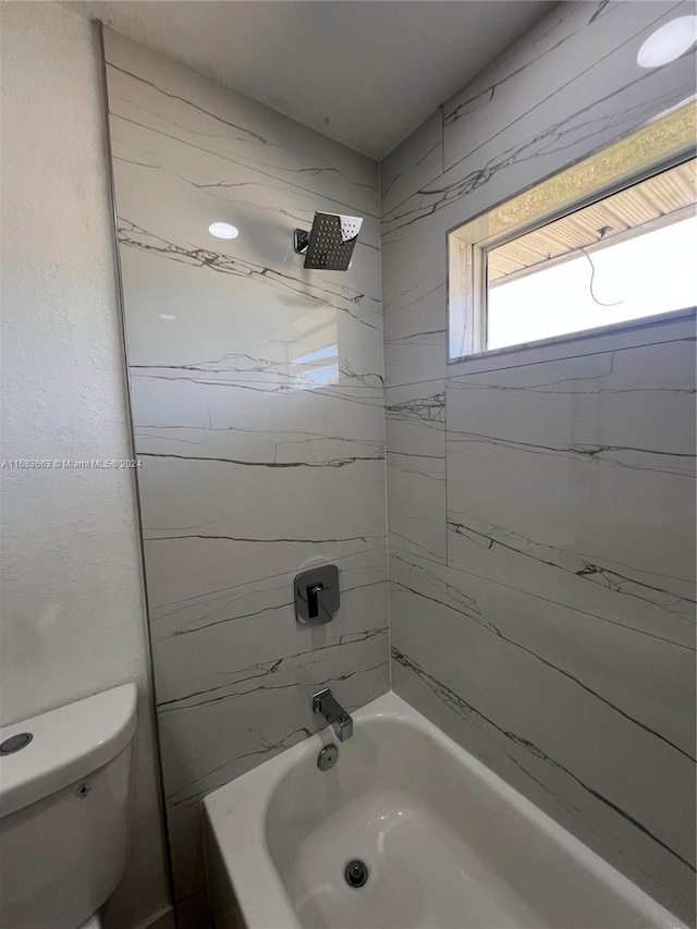 bathroom featuring tiled shower / bath and toilet