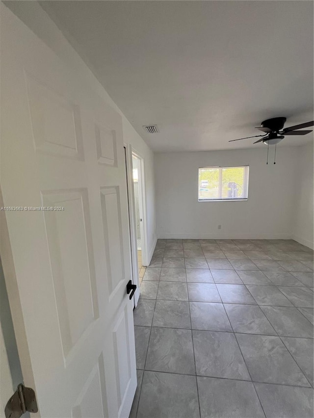 tiled spare room featuring ceiling fan