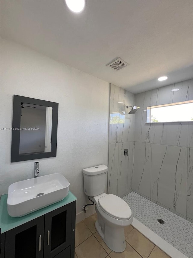 bathroom with vanity, tiled shower, toilet, and tile patterned floors