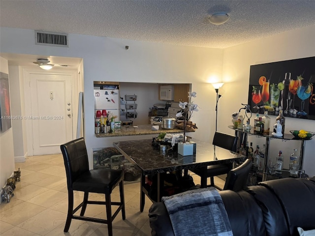 tiled dining room featuring a textured ceiling