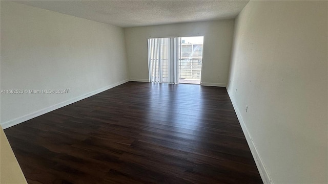 empty room with a textured ceiling and dark hardwood / wood-style flooring