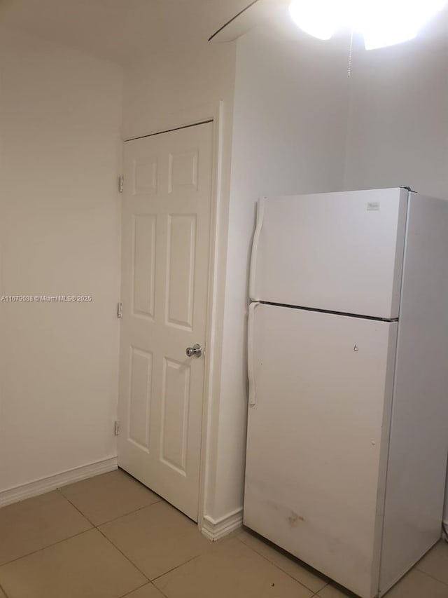 kitchen featuring light tile patterned floors, freestanding refrigerator, and baseboards