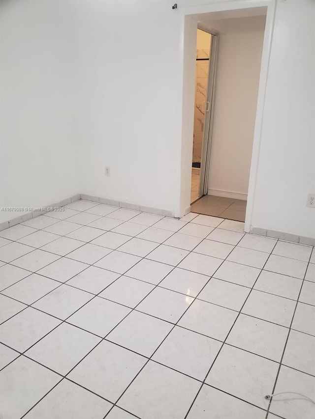 empty room featuring light tile patterned floors and baseboards