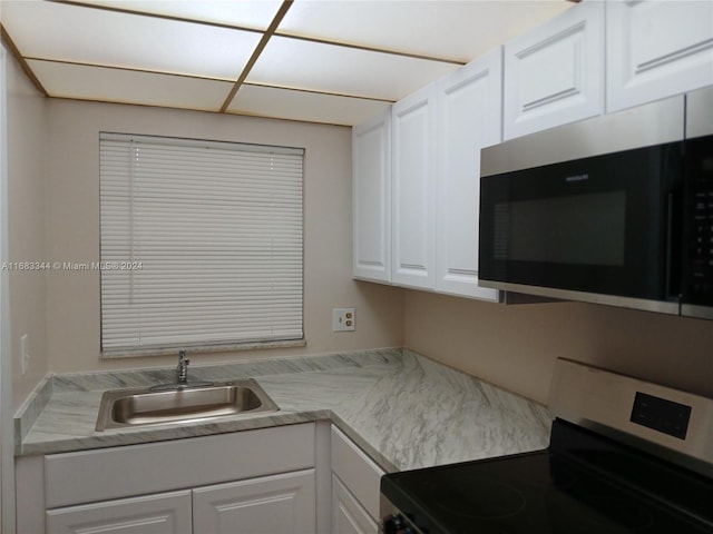 kitchen with sink, white cabinetry, and range