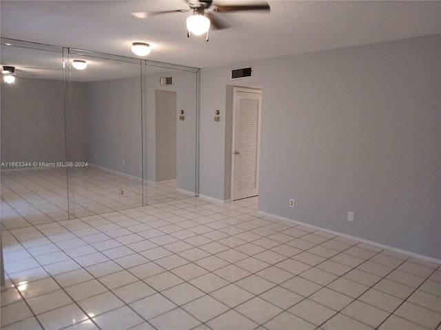 tiled spare room with a textured ceiling and ceiling fan