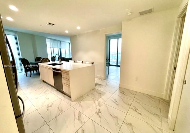 kitchen with sink, black dishwasher, stainless steel fridge, and a center island with sink