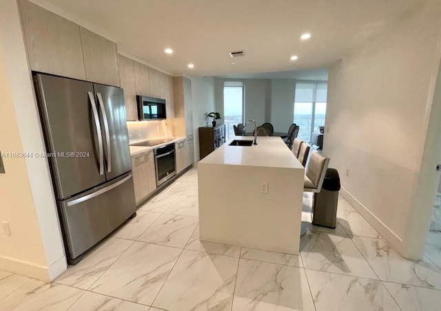 kitchen with sink, a breakfast bar, a kitchen island with sink, and appliances with stainless steel finishes