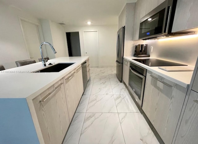 kitchen with stainless steel appliances, sink, decorative backsplash, a center island with sink, and gray cabinetry