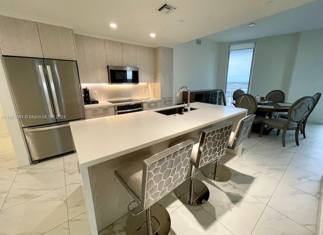 kitchen featuring sink, stainless steel appliances, a breakfast bar, and a center island with sink