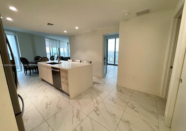 kitchen featuring sink, a center island with sink, stainless steel refrigerator, and black dishwasher