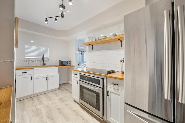 kitchen with wooden counters, sink, light wood-type flooring, white cabinetry, and appliances with stainless steel finishes