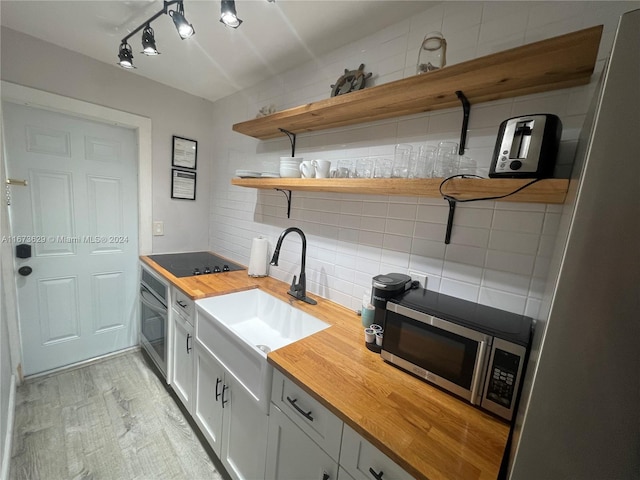 kitchen featuring wooden counters, decorative backsplash, sink, white cabinetry, and appliances with stainless steel finishes