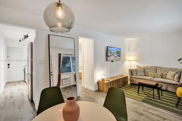 living room with an AC wall unit and light wood-type flooring